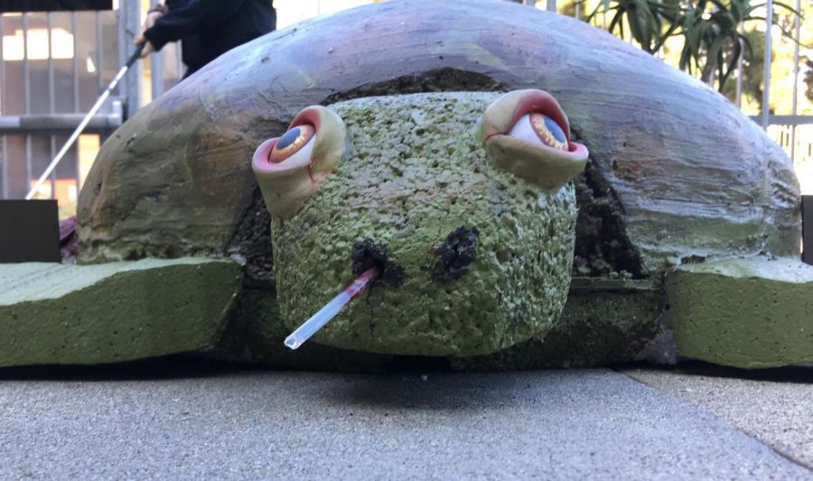 An art exhibit featuring a turtle with a straw in its nose.