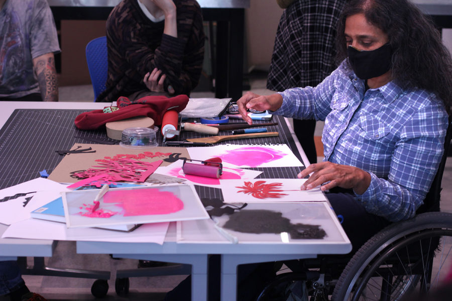 Artist Bhavna Mehta demonstrates cut paper art and printmaking to a group of people.