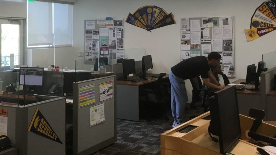 Joseph D’Ambro, senior student services assistant, stands behind a student and helps them fill out their transfer application on a computer