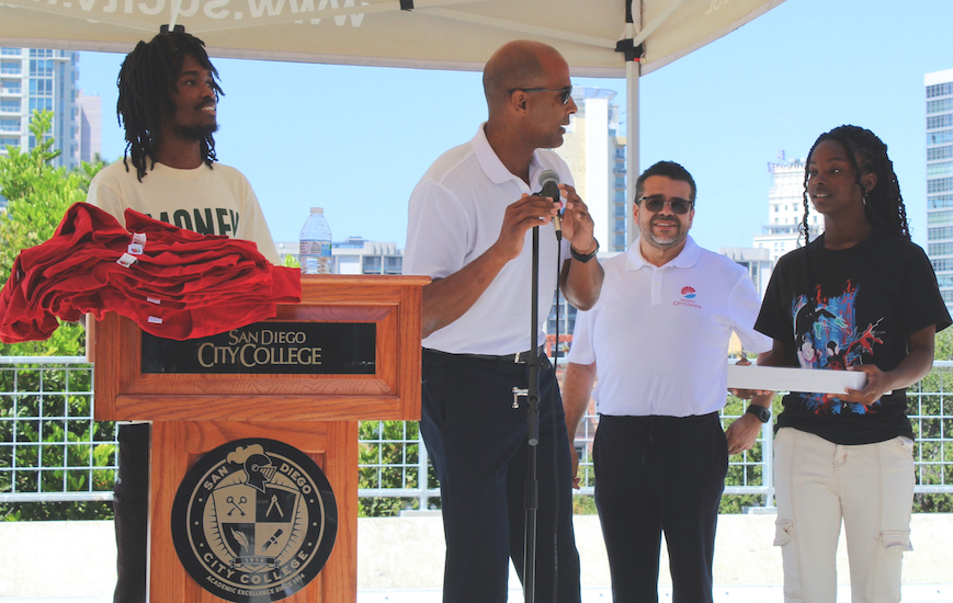 Los estudiantes Keymuandre Abdallah, a la izquierda, y Saika Didler, a la derecha, reciben nuevas laptops en el evento de Excelencia Negra el jueves 29 de agosto de 2024. El Vicepresidente de Servicios Administrativos, John Parker, con el micrófono, presenta a los ganadores mientras el Vicepresidente de Servicios Estudiantiles, Marciano Pérez, al fondo, observa. Foto de David J. Bohnet/City Times Media