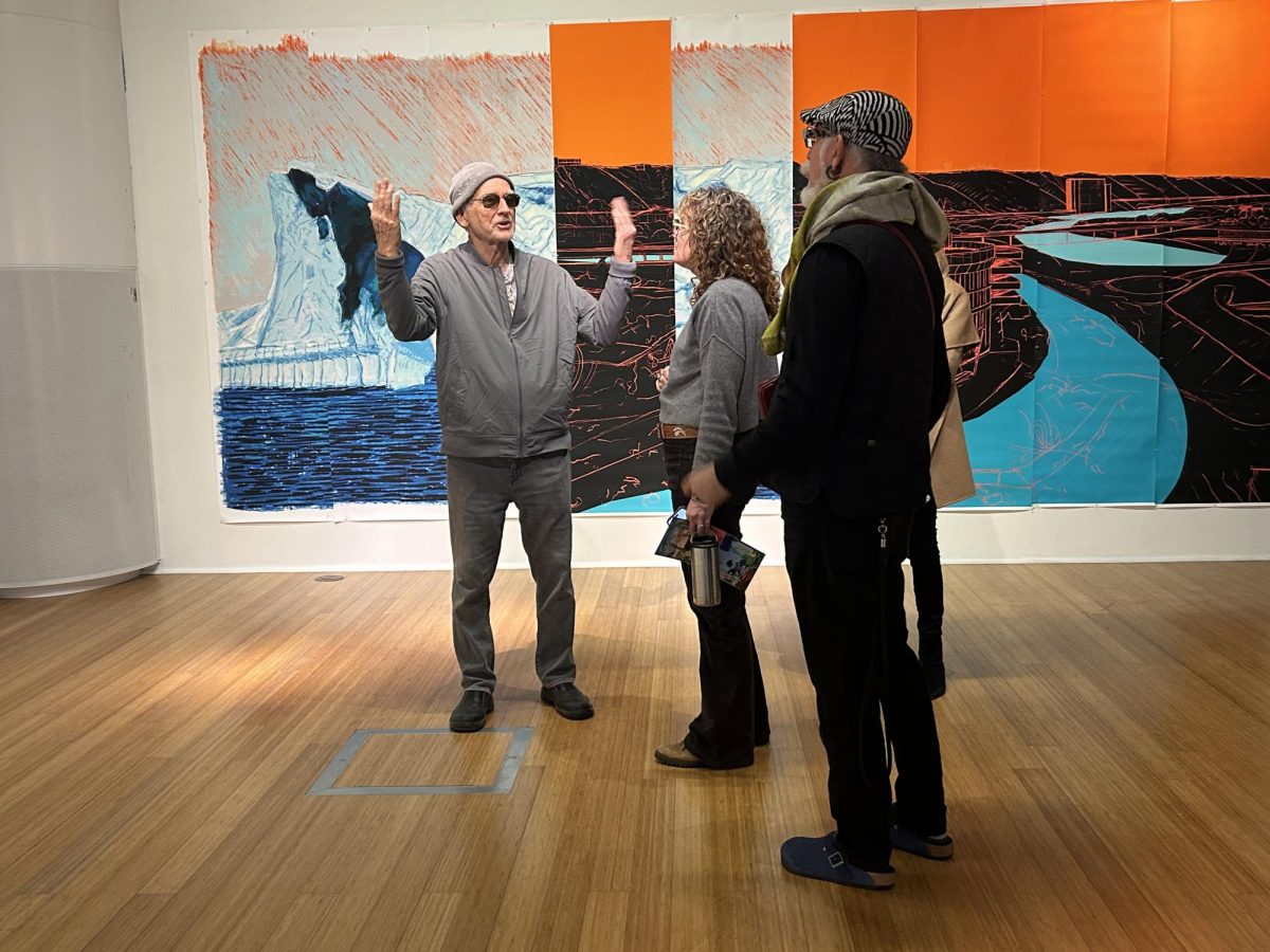 Bill Mosley, left, discusses the creative process for his cerulean paintings with Bridget Rountree, center, and Iain Gunn at the City Gallery, Thursday, Feb. 6, 2025. Photo by Nadia Lavin/City Times Media